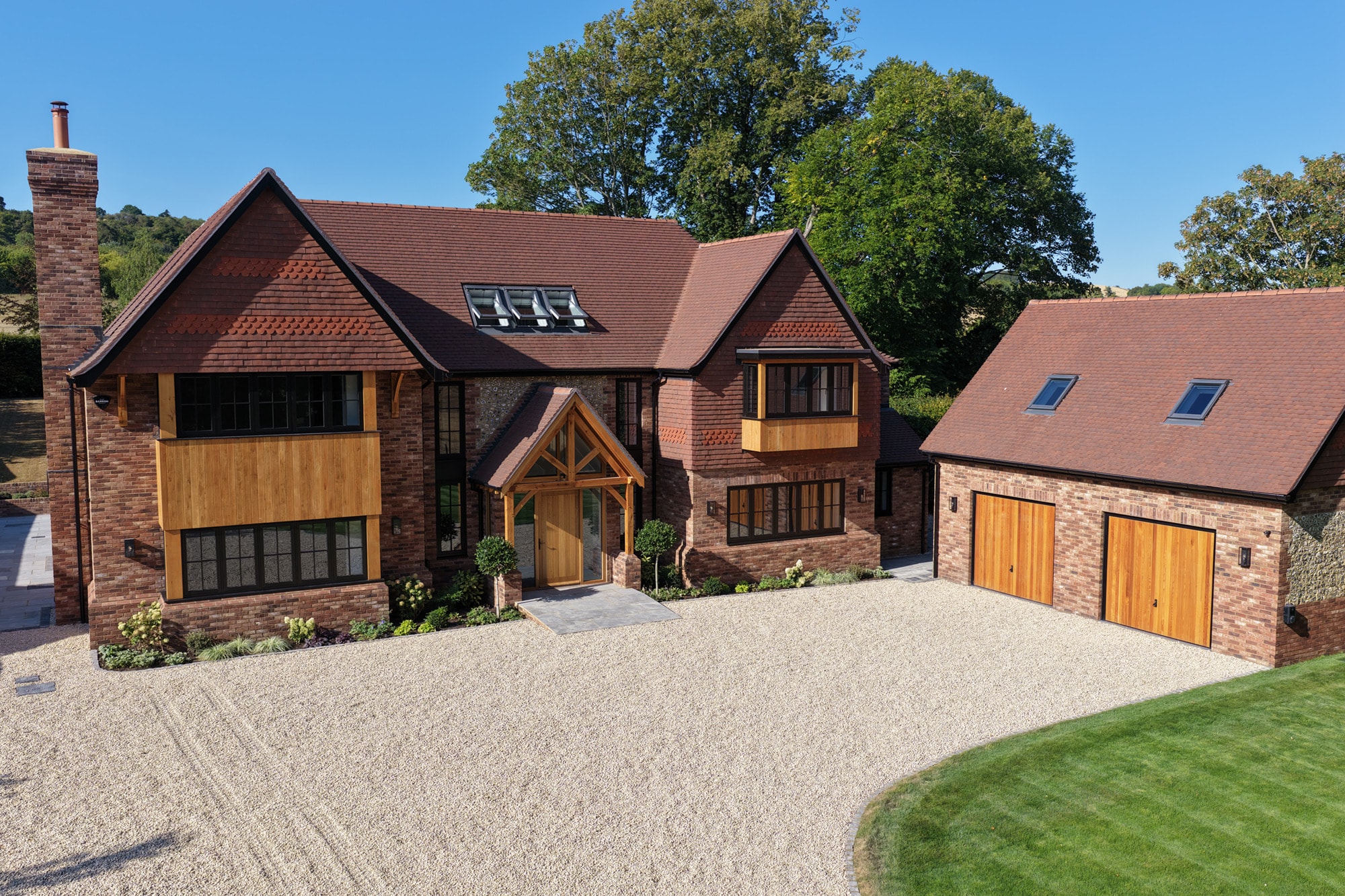 Aerial view of a brick house with a tiled roof, timber porch and detached garage