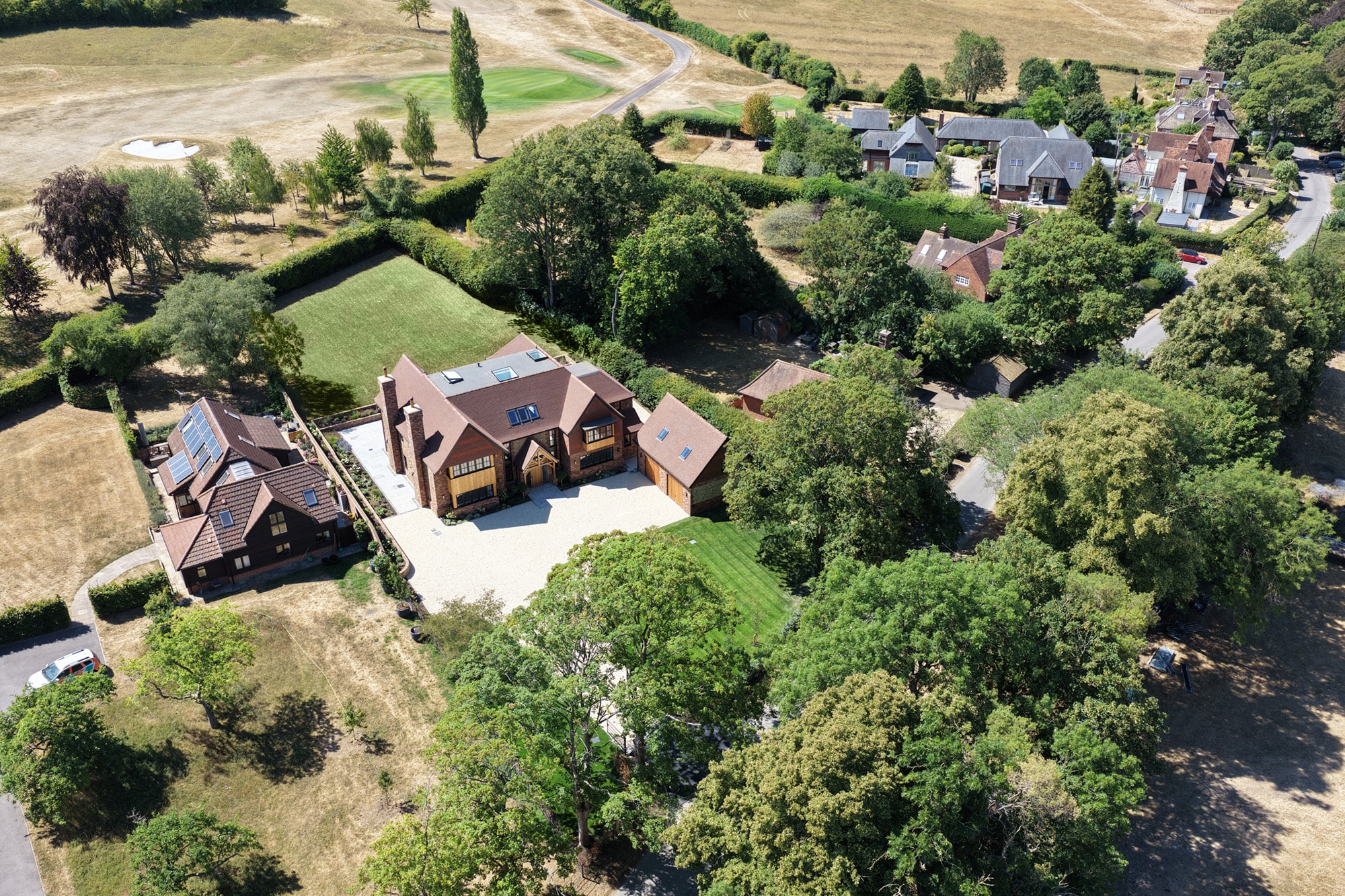 Aerial view of a large brick house and garden beside open fields